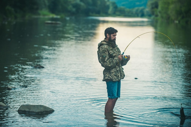 Attrapez des poissons tenant un portrait de truite brune d'un pêcheur à la ligne d'un homme gai