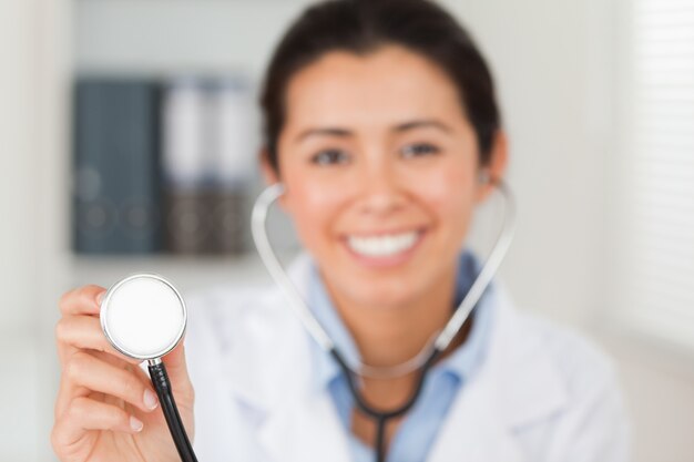 Attrayant femme médecin à l&#39;aide d&#39;un stéthoscope tout en regardant la caméra