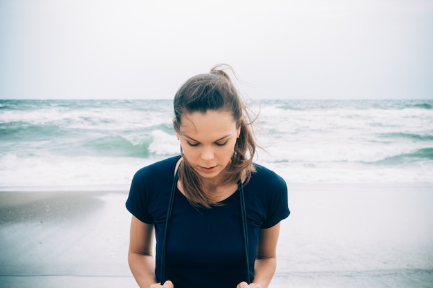 Attrayante athlète féminine avec une corde à sauter sur la plage par temps froid