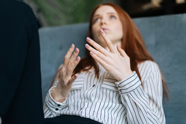 Attrayante jeune femme aux cheveux roux patiente allongée sur un fauteuil confortable et racontant ses problèmes au psychothérapeute. Dame déprimée parlant avec un médecin pendant la thérapie de conseil.