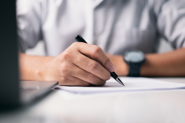 Au bureau, un homme d'affaires signe un document papier.