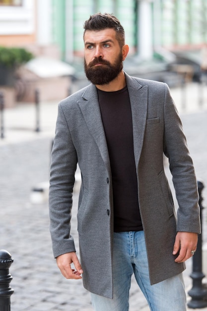 Au centre-ville. Homme barbu va travailler. Le début de la journée de travail. Hipster dans le style d'affaires dans la rue. Homme d'affaires dans la ville moderne. Homme d'affaires professionnel menant un style de vie occupé.