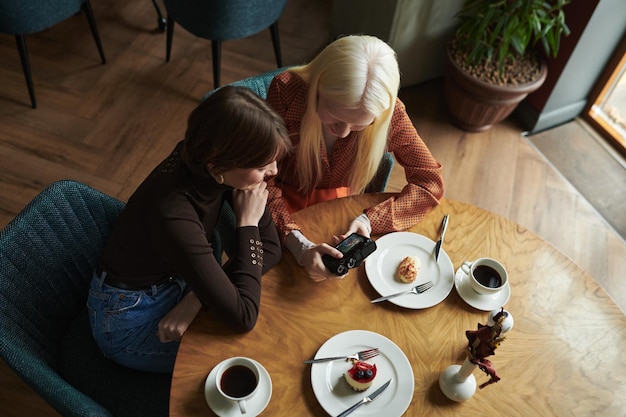 Au-dessus de l'angle de deux jeunes femmes regardant à travers des photos dans un appareil photo