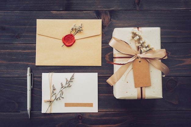 Au-dessus d'une boîte-cadeau artisanale et d'une carte de voeux avec un stylo sur fond de table en bois