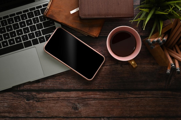 Au-dessus de l'espace de travail avec ordinateur portable tasse à café porte-crayon et pone mobile