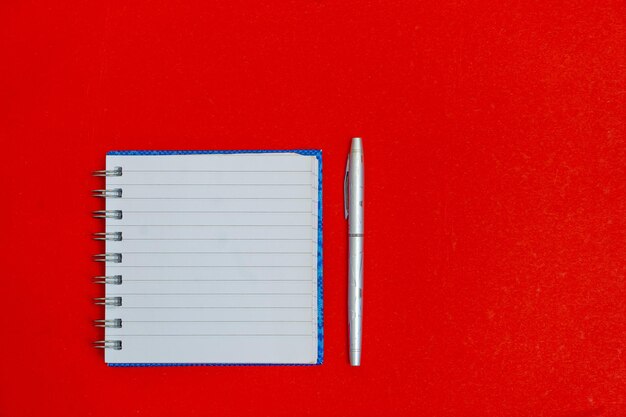 Au-dessus de flatlay voir photo d'ouvrir clair avec un cahier d'espace vide sur fond rouge isolé en spirale