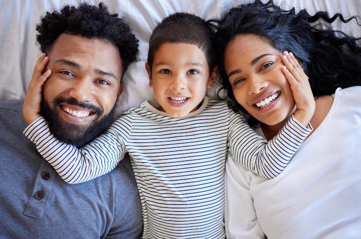 Photo au-dessus le garçon de la famille et le portrait heureux sur le lit pour le matin la paix le temps de liaison et la relation la confiance à la maison les parents le jeune enfant et sourire ensemble sur le matelas pour se réveiller se détendre et le soutien de l'amour