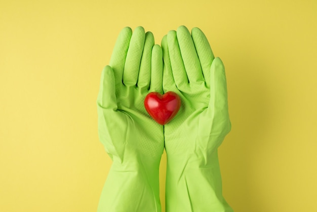 Au-dessus de la photo pov du coeur rouge et des mains dans des gants verts isolés sur fond jaune