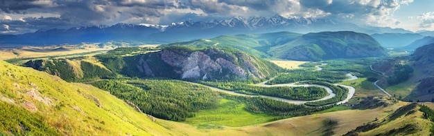 Au-dessus d'une vallée de montagne pittoresque avec une rivière, lumière du soir, vue panoramique