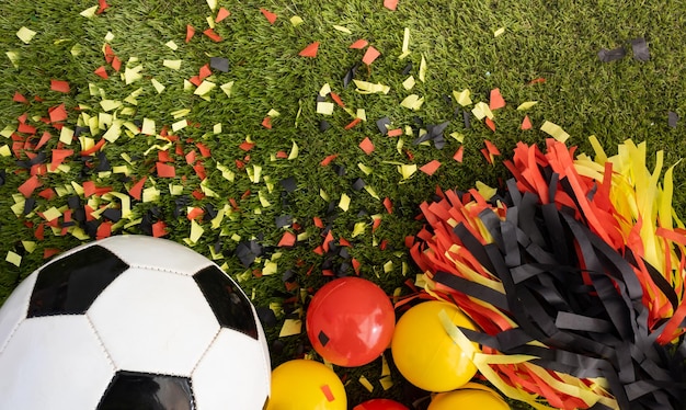 Photo au-dessus de la vue du ballon de football et des cotillons noirs jaunes et rouges