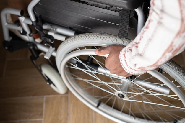 Au-dessus de la vue de la main d'un jeune homme handicapé faisant tourner la roue du fauteuil roulant