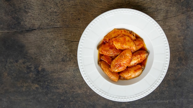 Au four ailes de poulet sur plat sur fond en bois