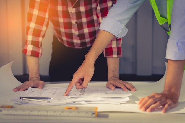 Au milieu de la planification de l'ingénieur avec un collègue sur le plan sur le chantier de construction