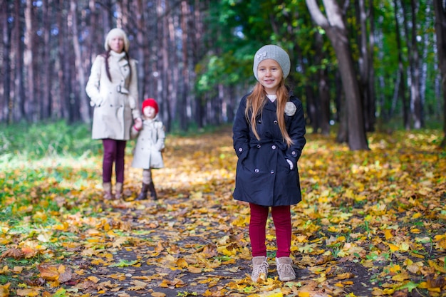 Au premier plan, une jolie fille douce derrière sa mère et sa sœur au parc en automne