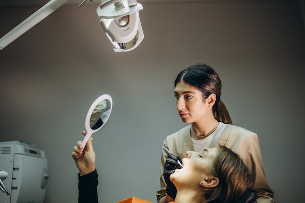 Au rendez-vous du dentiste La fille regarde dans le miroir ses dents