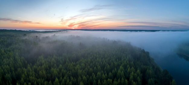 Aube d'été sur la forêt brumeuse et la vue aérienne du drone sur la rivière Paysage panoramique aérien avec coucher de soleil sur la rivière et beaux nuages dans le ciel