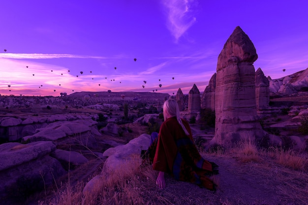 Aube Magique à Göreme Cappadoce Turquie. Une Fille Dans Un Canyon En Vêtements Traditionnels Entourée De Ballons Dans Les Rayons Du Soleil Levant