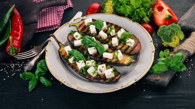 Aubergine grillée au fromage feta et basilic Nourriture saine Sur une table en bois noir Vue de dessus Espace libre pour le texte