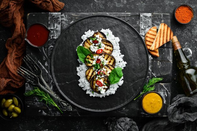 Aubergine grillée avec riz et fromage sur une plaque noire Vue de dessus Style rustique