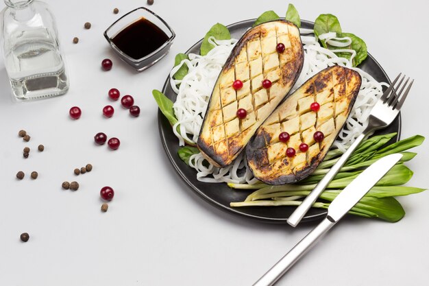 Aubergines au four avec des verts et des nouilles de riz sur plaque noire