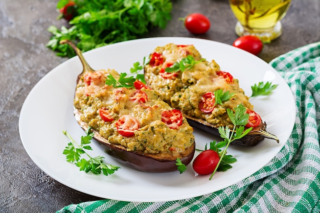 Aubergines farcies à la viande hachée de poulet et de légumes sur un fond gris.