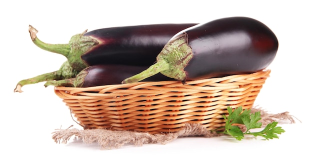 Aubergines fraîches dans le panier en osier isolé sur blanc