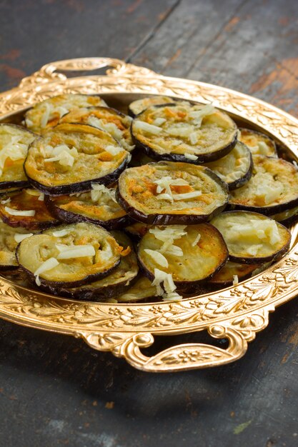 Aubergines frites à l'ail dans un plat doré vintage