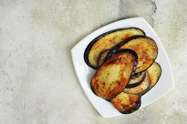 Aubergines frites sur une assiette sur un fond gris - espace copie vue de dessus