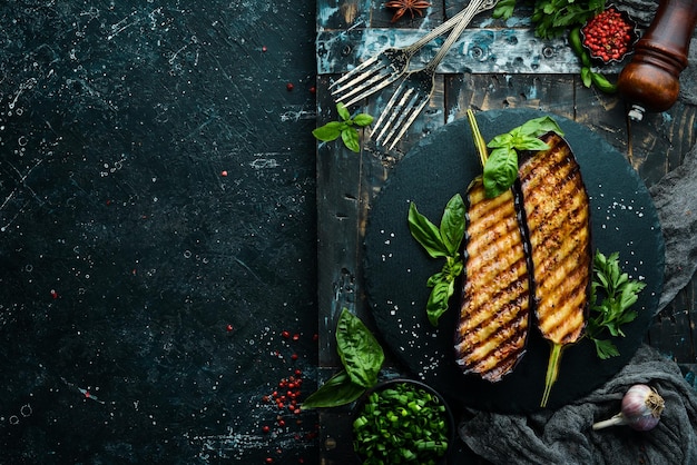 Aubergines grillées au basilic sur une plaque en pierre noire Vue de dessus Espace libre pour votre texte