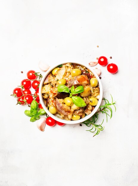 Aubergines mijotées avec légumes et herbes dans un bol vue de dessus sur fond clair