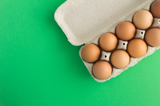 Photo aucun concept d'emballage en plastique. faire dorer les œufs de poule dans la boîte en carton sur la surface verte. vue de dessus. copiez l'espace.