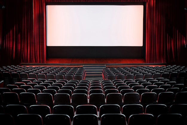 Auditorium d'une salle de cinéma vide et scène avec des rideaux de velours rouge ouverts