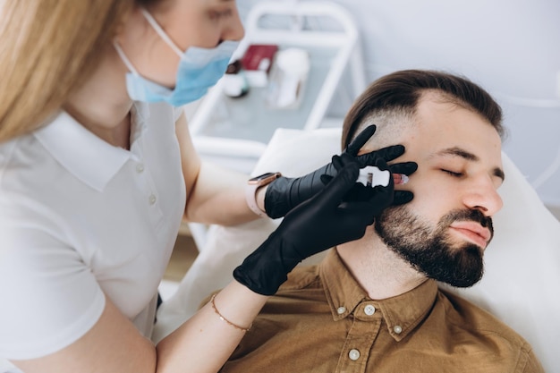 Augmentation de la taille des lèvres pour les hommes Injection d'acide hyaluronique dans les lèvres d'un jeune homme barbu élégant