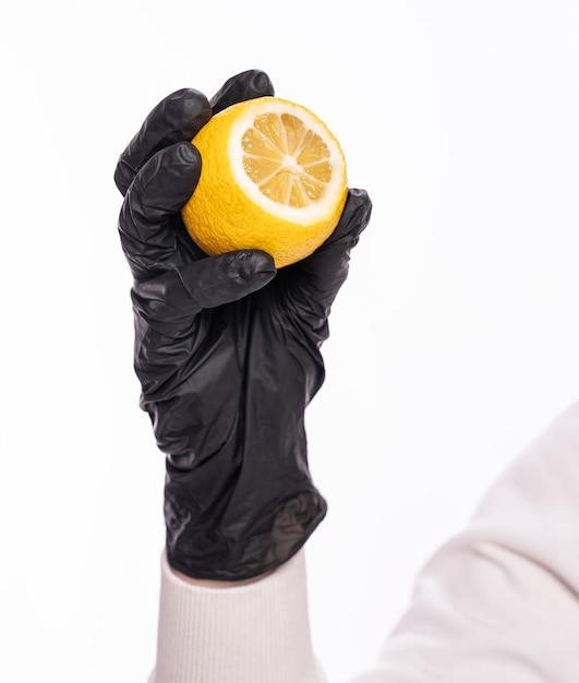 Augmenter l'immunité et le concept de soins de santé. Femme en gant de protection tenant un citron sur fond blanc