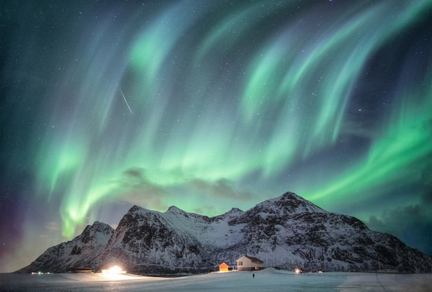 Aurora borealis avec chaîne de montagnes étoilée sur la neige et illumination à Flakstad