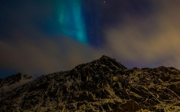 Aurore boréale avec ciel nuageux sur la montagne à Leknes