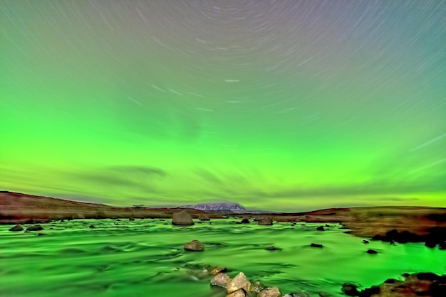 Les aurores boréales allument la rivière et la traînée d'étoiles longue exposition