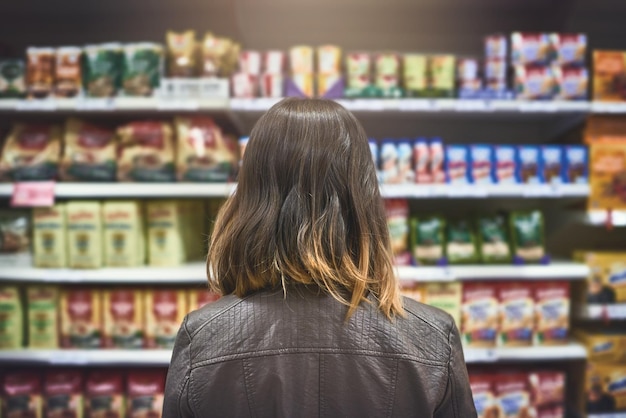 Autant de marques Vue arrière d'une jeune femme faisant ses courses dans une épicerie