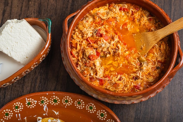 Authentique poulet mexicain tinga cuisine mexicaine typique préparée dans un pot en argile sur une table en bois