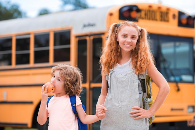 Autobus scolaire et portrait d'enfants heureux d'un petit frère et d'une soeur heureux debout ensemble devant...