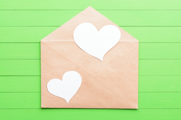 Autocollant blanc en forme de coeur dans une enveloppe sur fond de bois vert