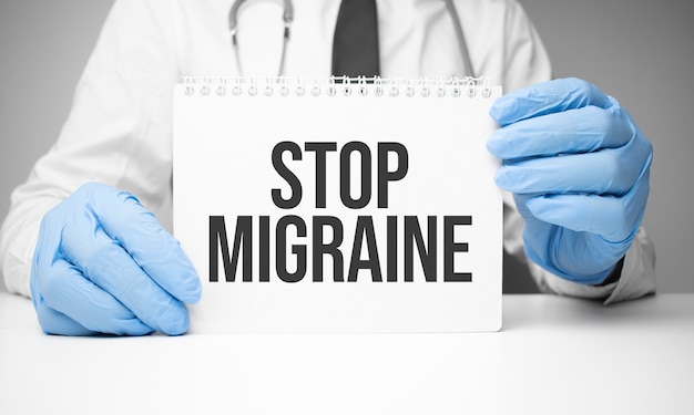 Autocollant blanc avec texte Stop Migraine dans les mains du médecin avec un stéthoscope