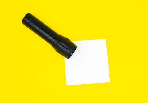 Autocollant de liste de tâches blanc vierge avec lampe de poche noire Recherche d'informations sur InternetxACerre du papier de rappel sur fond jaune Espace de copie Minimalisme original et créatif