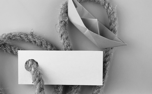 Photo autocollant photo monochrome avec corde tressée épaisse et origami papier bateau