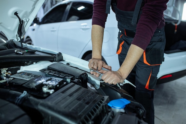 Un automech masculin inspecte le moteur de la voiture. Service de voiture et réparation de voiture.