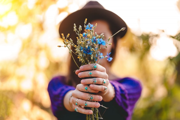 Automne brunette woman wearing silver rings avec turquoise stone détient bouquet de fleurs sauvages dans les mains dans la forêt d'automne à l'extérieur à l'automne