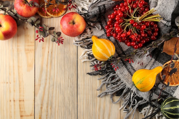 Automne. composition d'automne avec un plaid chaud, des feuilles jaunes, des citrouilles décoratives et des pommes sur un fond en bois naturel. vue de dessus