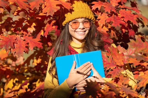 Automne enfant fille visage sur fond de feuille d'automne Automne enfant adolescent fille 12 13 14 ans portrait heureux enfant tenir livre sur fond de feuilles d'automne retour à l'école