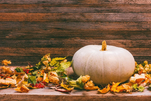 Automne nature morte avec citrouille et feuilles sèches sur un fond en bois