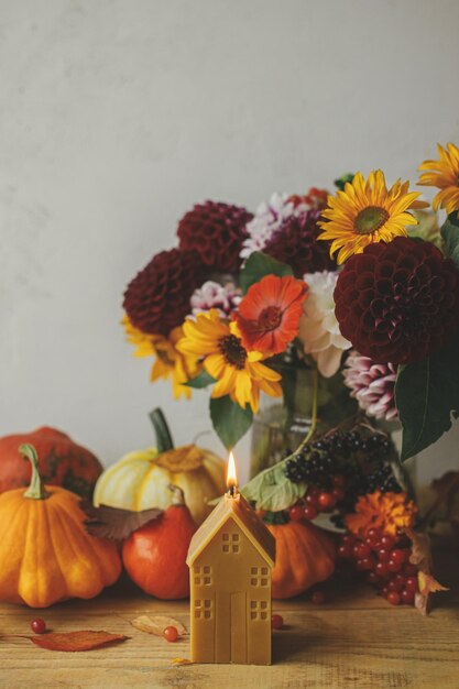 Photo automne nature morte citrouilles fleurs d'automne baies feuilles bougie sur table en bois thanksgiving